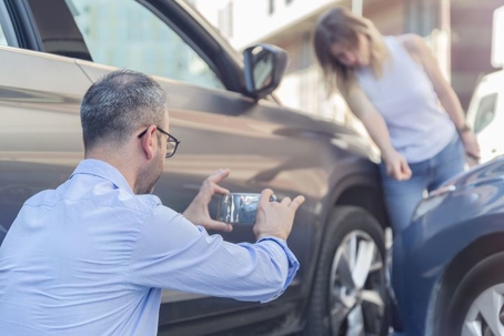 man taking photo of cars after accident