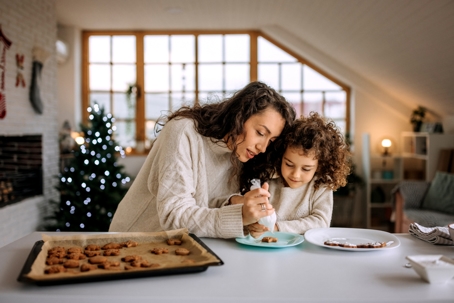 mother and daughter decorating cookies during the holidays