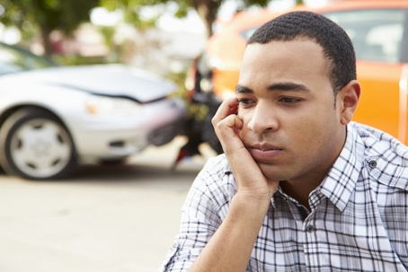worried man sitting by car after accident