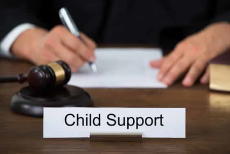 sign with "child support" written on it next to a gavel and a man signing a contract